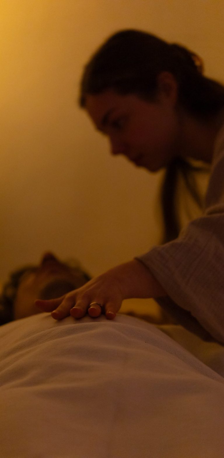 Atemprozess in Leipzig Eine Person beugt sich über eine ruhende Person in einem sanften, warmen Licht.